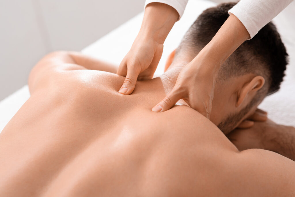 Closeup of man getting acupressure massage at spa salon, top view. Female masseuse massaging unrecognizable man shoulders, pain relief for sportsmen, businessmen and office workers